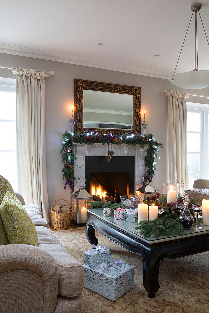 Fairylights on Christmas garland above lit fire with lit candles in living room of Chobham home   Surrey   England   UK