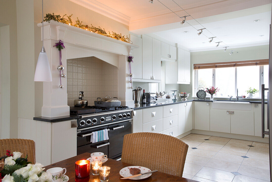 Lit candle on table in white fitted kitchen of Chobham home   Surrey   England   UK