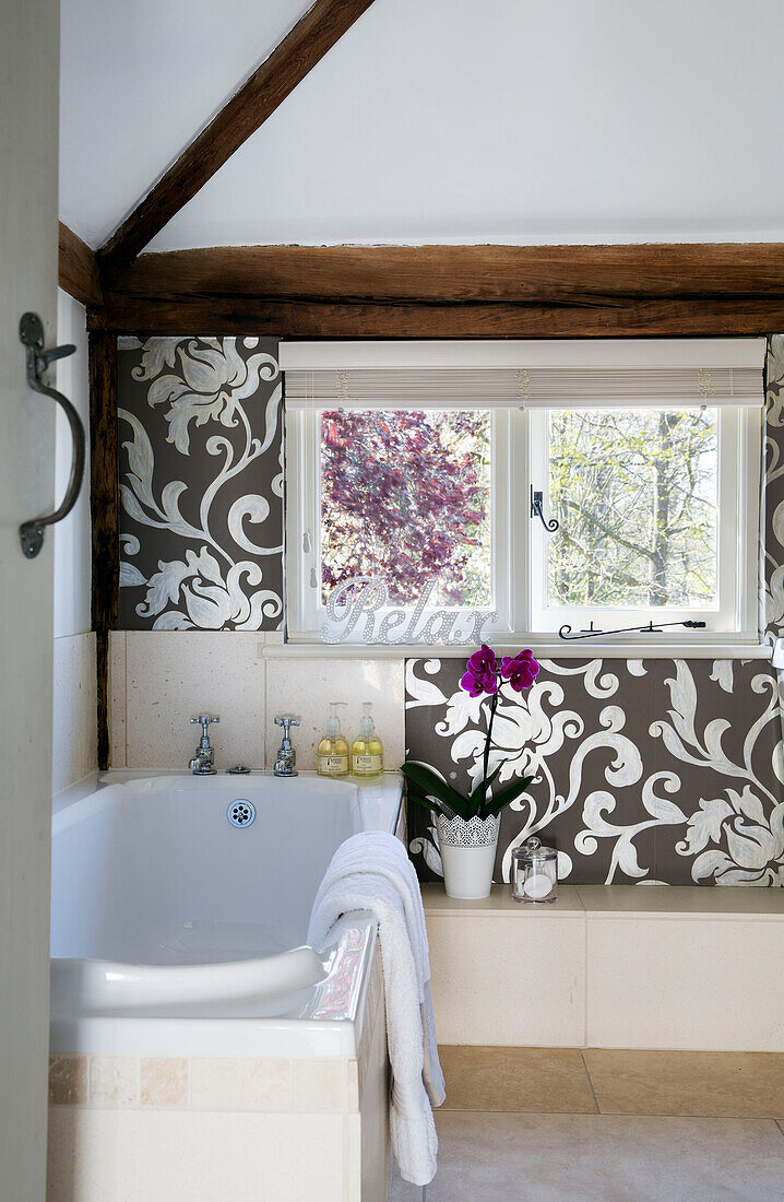 Silver metallic wallpaper on window surround with bath in Sandhurst country house  Kent  England  UK