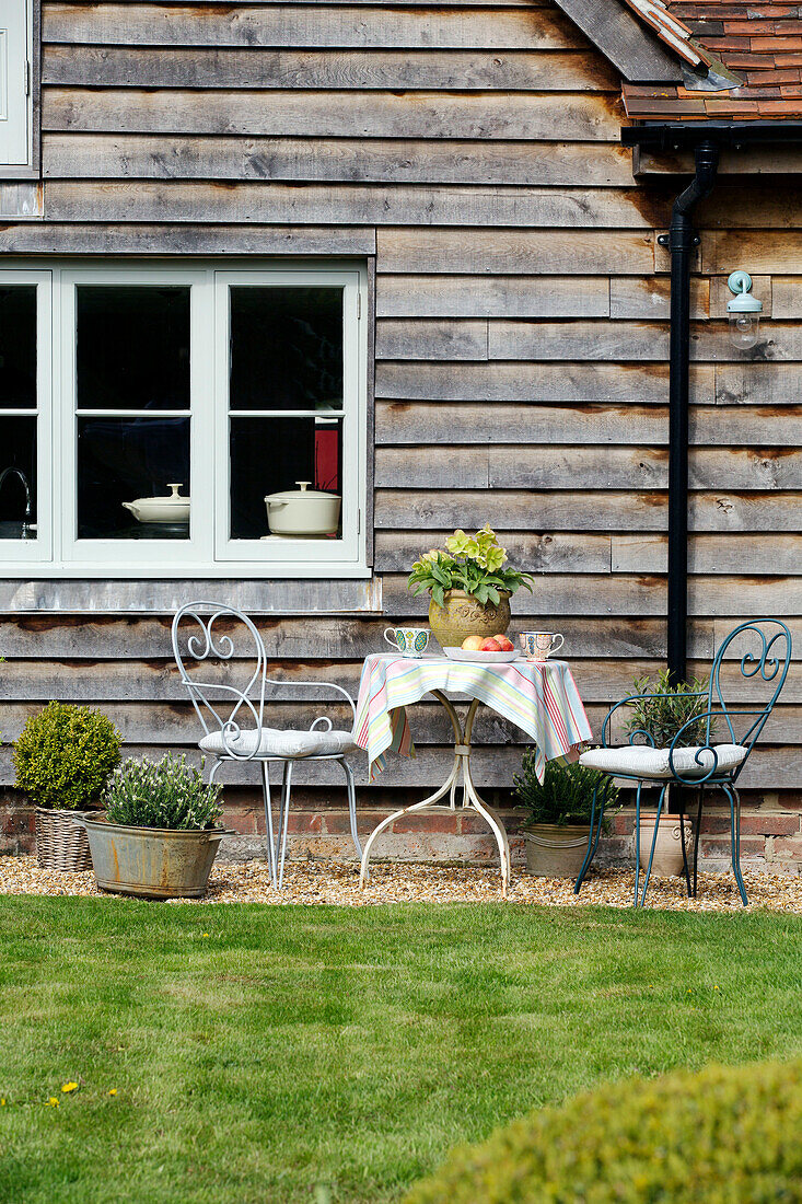 Table and chairs at window of weatherboard exterior  East Dean  West Sussex  UK