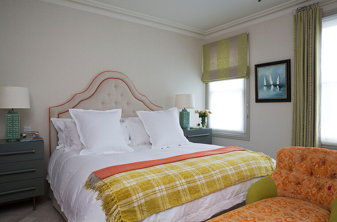 Checked yellow blanket on double bed with chaise longue in London home, England, UK