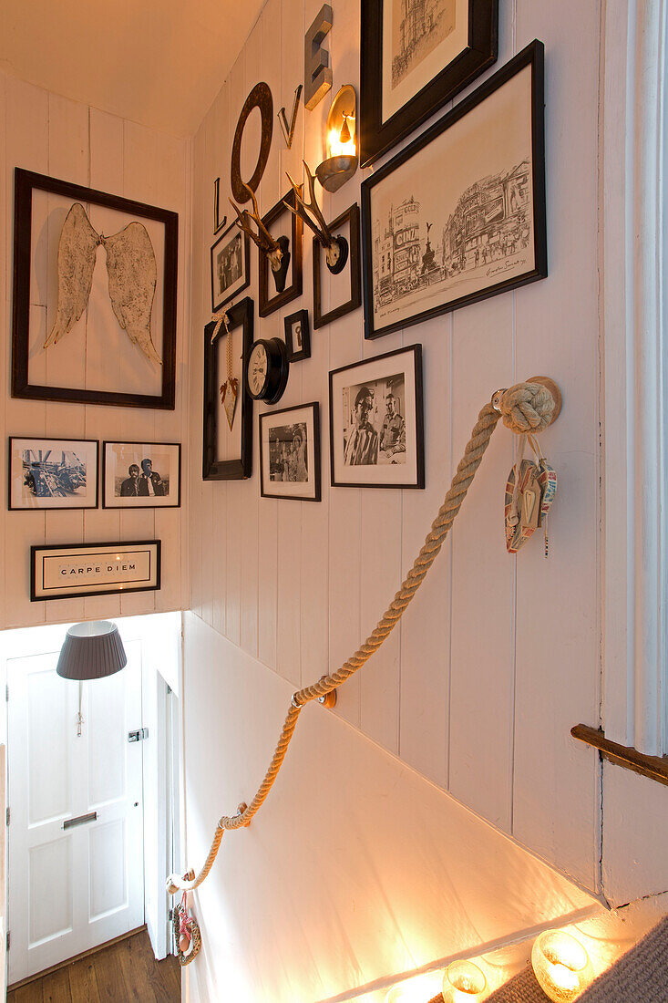Framed artwork displayed above rope handrail in staircase of Surrey home   England   UK