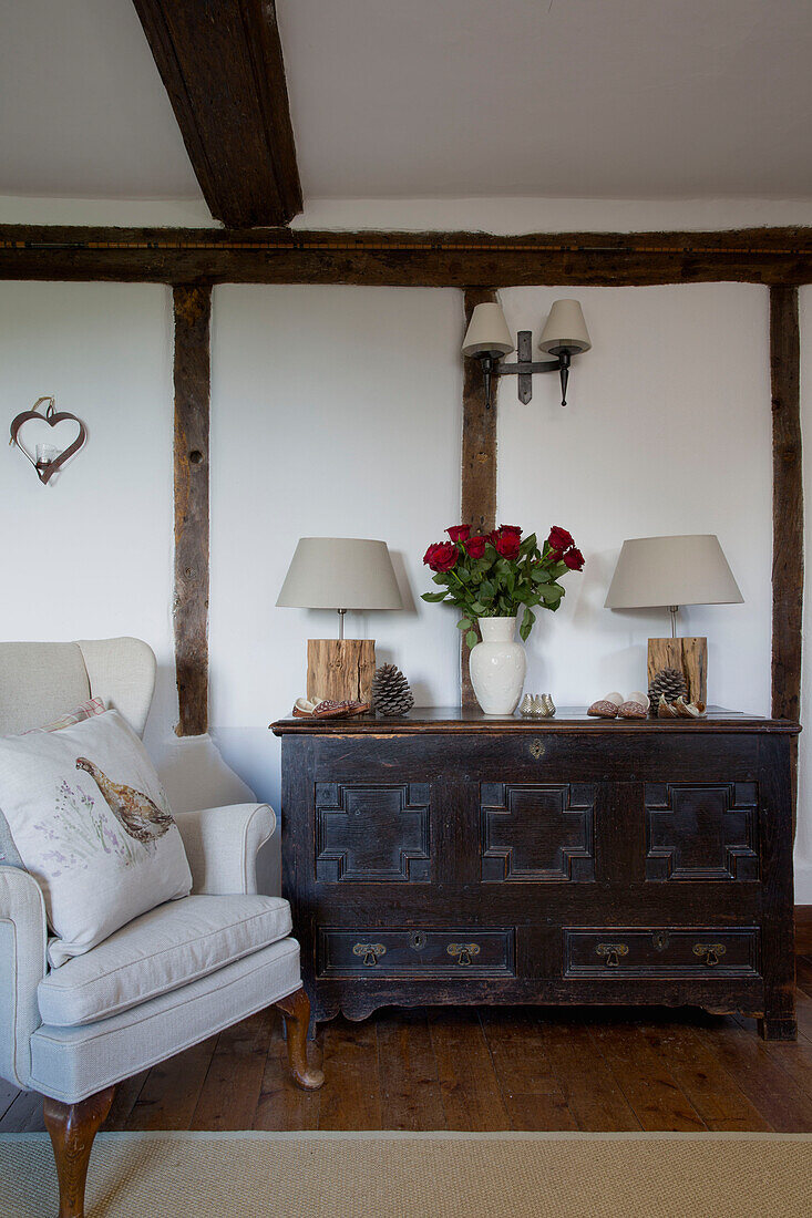 Vintage-Truhe mit geschnittenen Rosen und Ohrensessel in Fachwerkbauernhaus in Sussex England UK