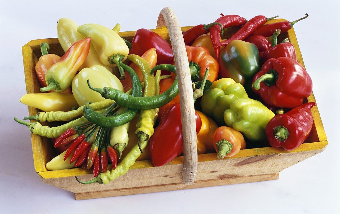 Various types of peppers & chili peppers in wooden basket