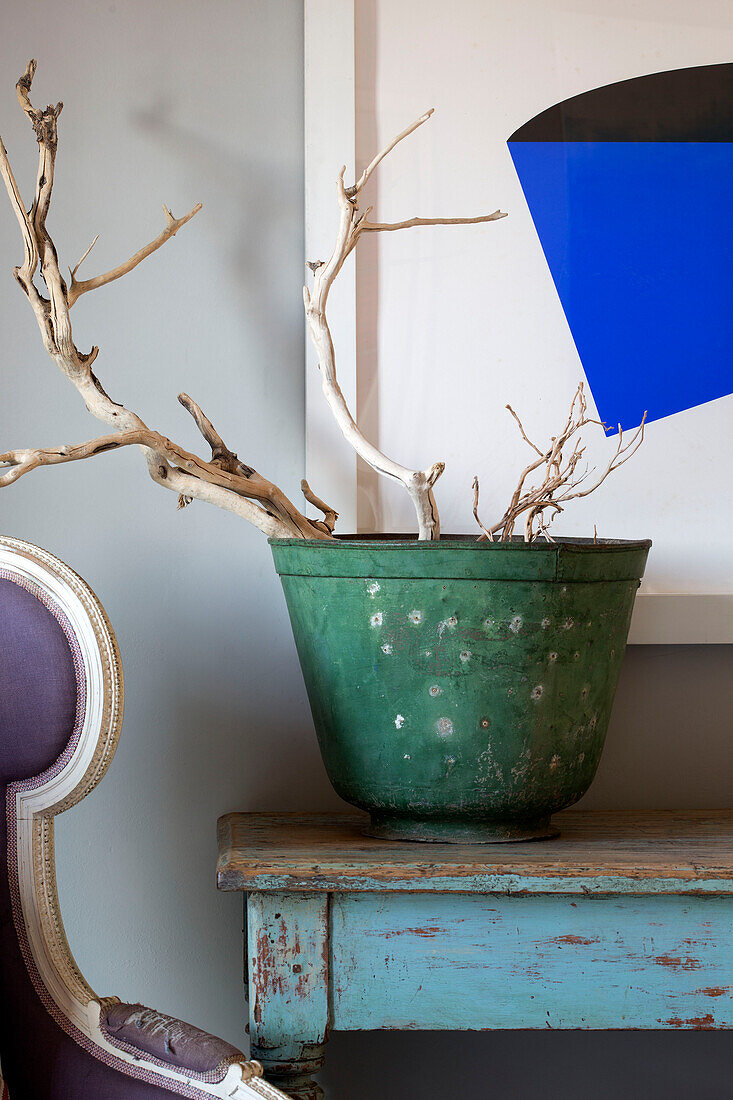 Green plant pot with bright blue artwork and wooden console in 18th century Ithaca townhouse Greece