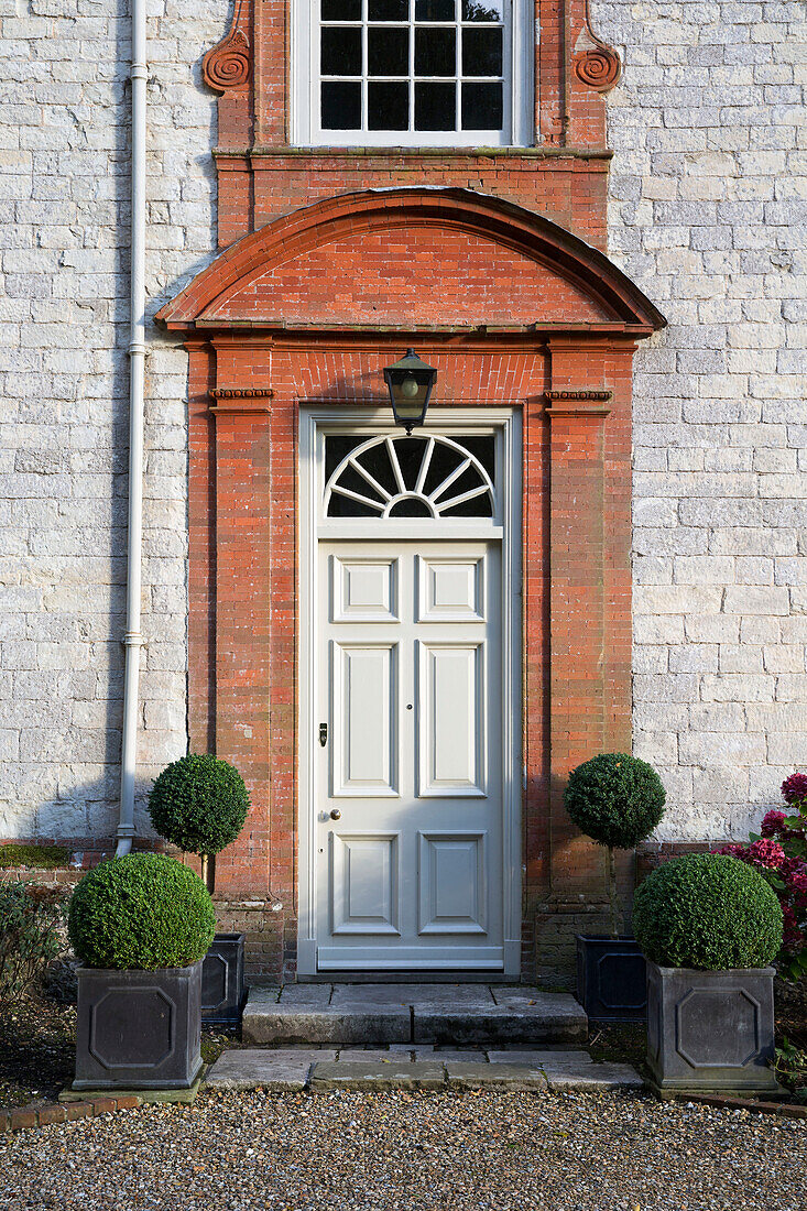 Gravel driveway and front door of stone and brick Sussex country house England UK