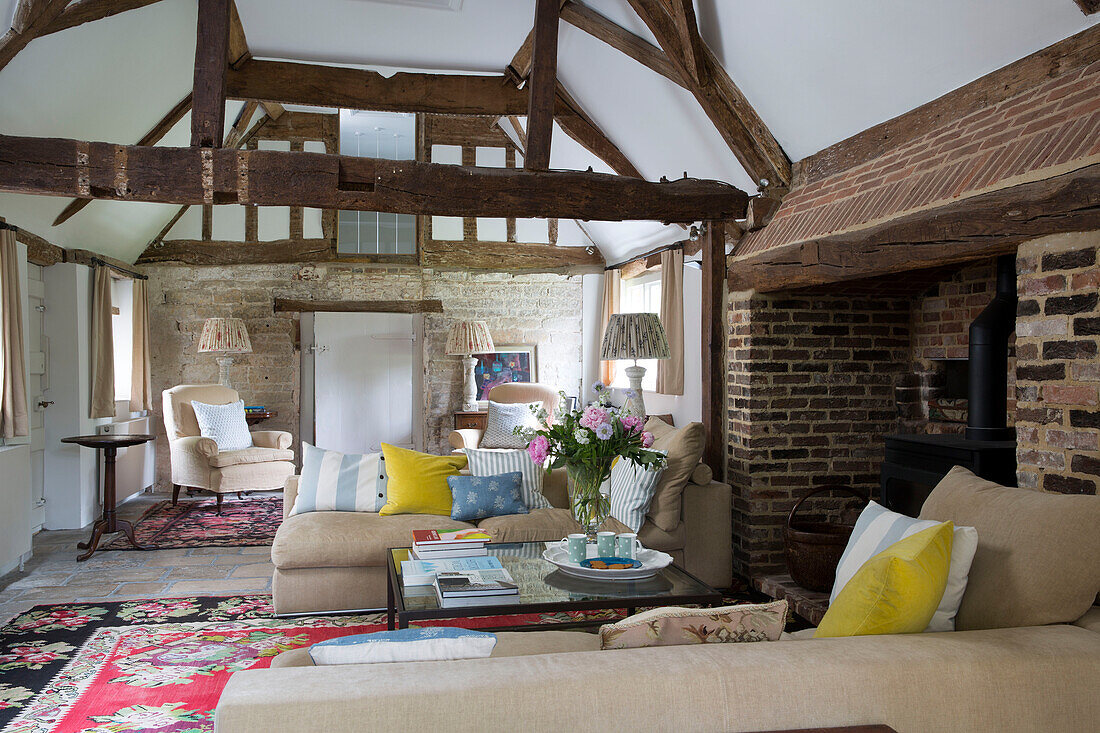 Freigelegte Steinmauer im Wohnzimmer mit Balken in einem Landhaus in Sussex, England UK