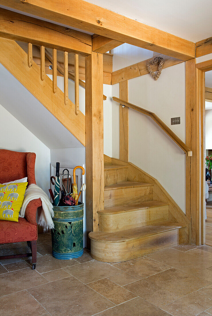 Sessel und Schirmständer unter einer Holztreppe in einem Haus in Surrey England UK