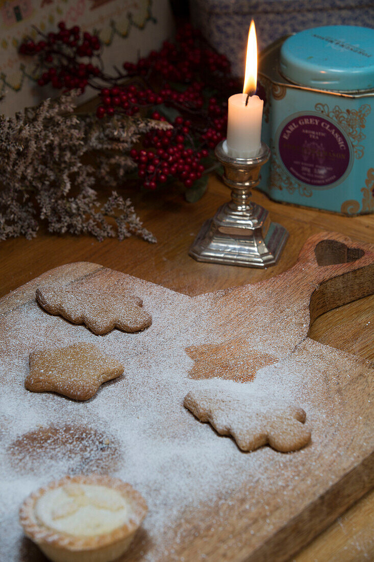 Beleuchtete Kerze mit Weihnachtskeksen auf einem Schneidebrett in London, England, UK