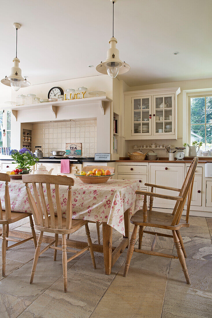 Cream pendant lights above kitchen table in renovated Victorian schoolhouse West Sussex England UK