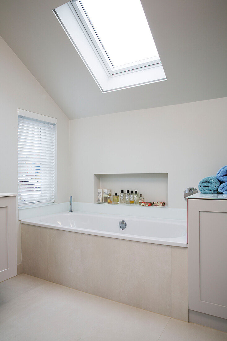 Marble bath below skylight window in modernised Victorian cottage Sussex England UK