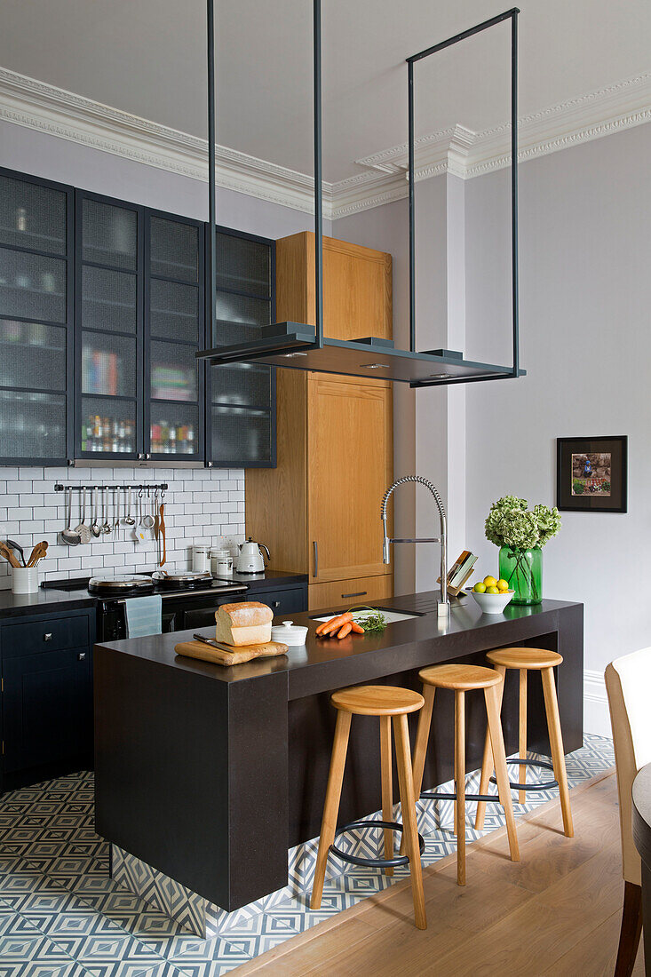 Wooden stools at breakfast bar in modern kitchen of London townhouse UK