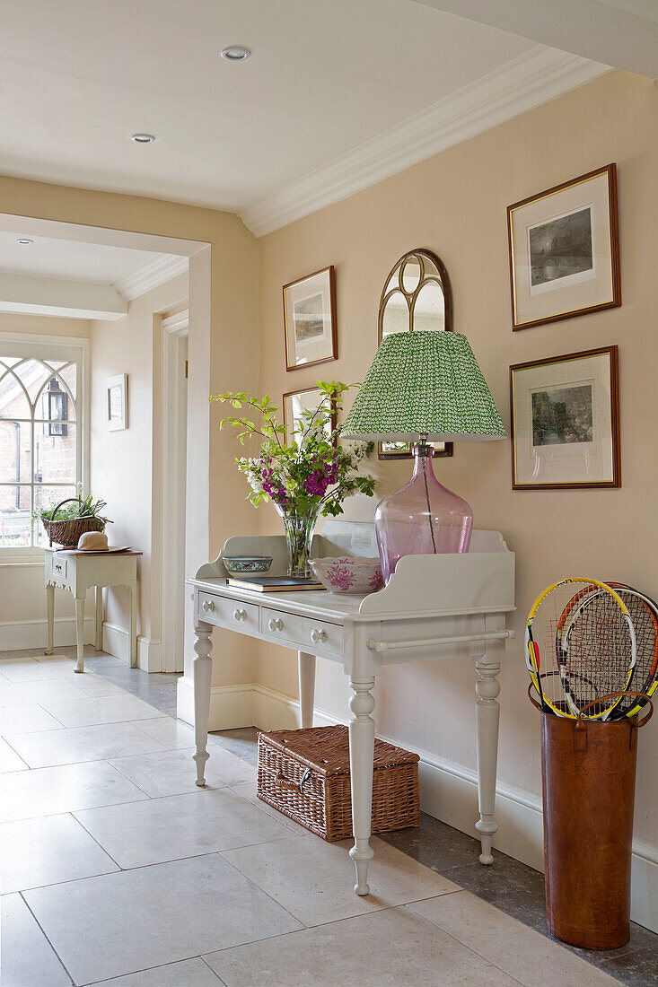 Cut flowers and lamp on white painted desk with basket in hallway of Grade II listed Georgian country house in Shropshire England UK