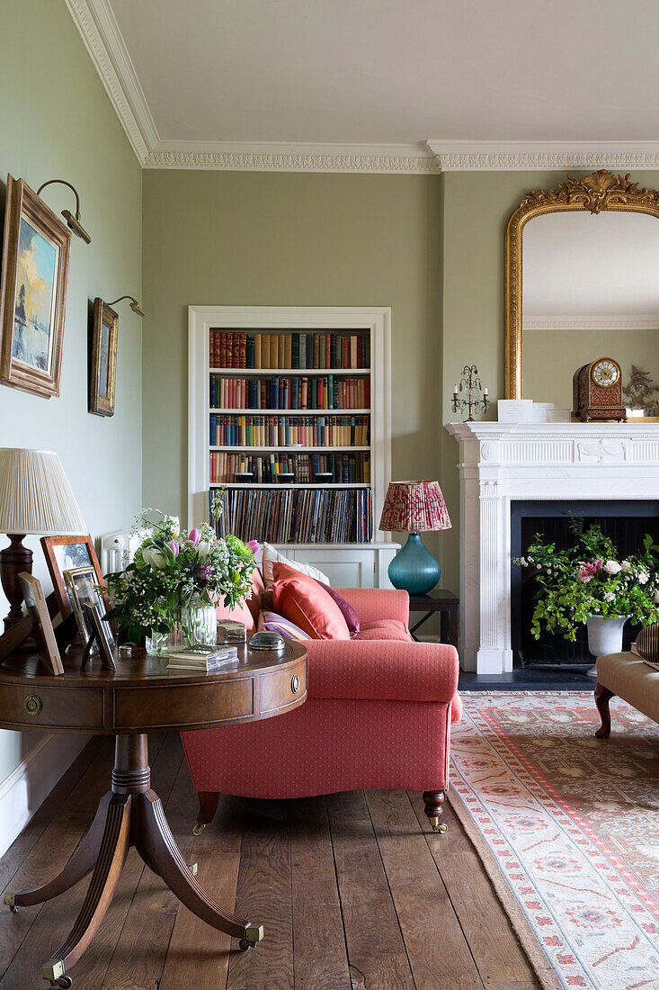 Antiker Holztisch mit Sofa und eingelassenen Bücherregalen in einem unter Denkmalschutz stehenden georgianischen Landhaus in Shropshire England UK