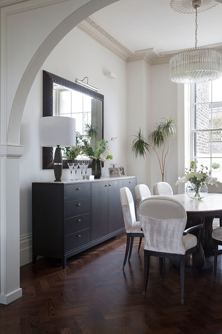 Dark wooden sideboard with polished parquet floor in dining room of London townhouse England UK