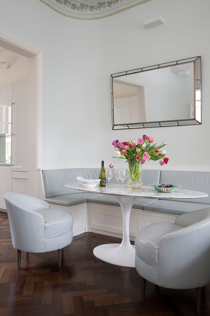 White leather armchairs and oval Tulip table with bench seating in London townhouse England UK