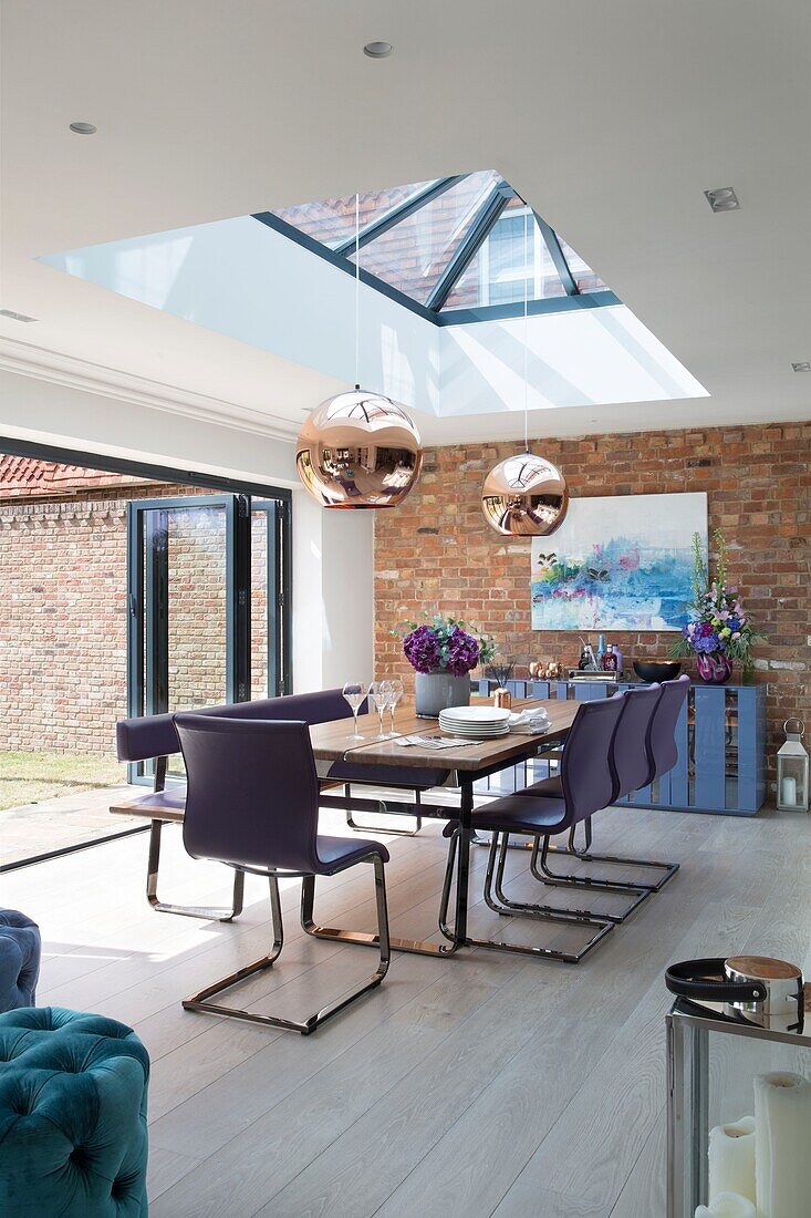 Modern extension with exposed brick wall and skylight pendant shades in Sussex home England UK