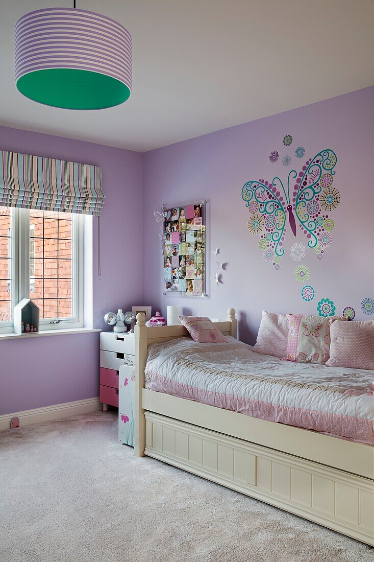 Butterfly wall deco above single bed with pink quilt in lilac bedroom in Sussex home England UK