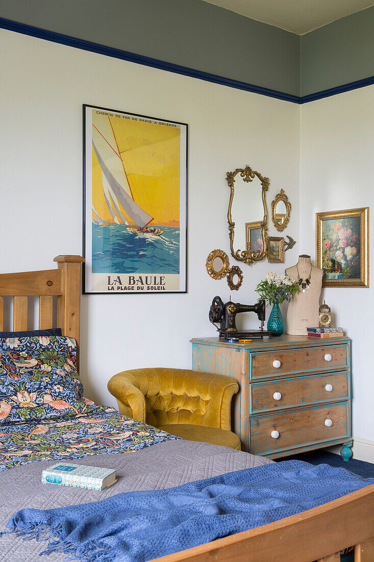 Buttoned mustard armchair with framed print at bedside in Yorkshire home England UK