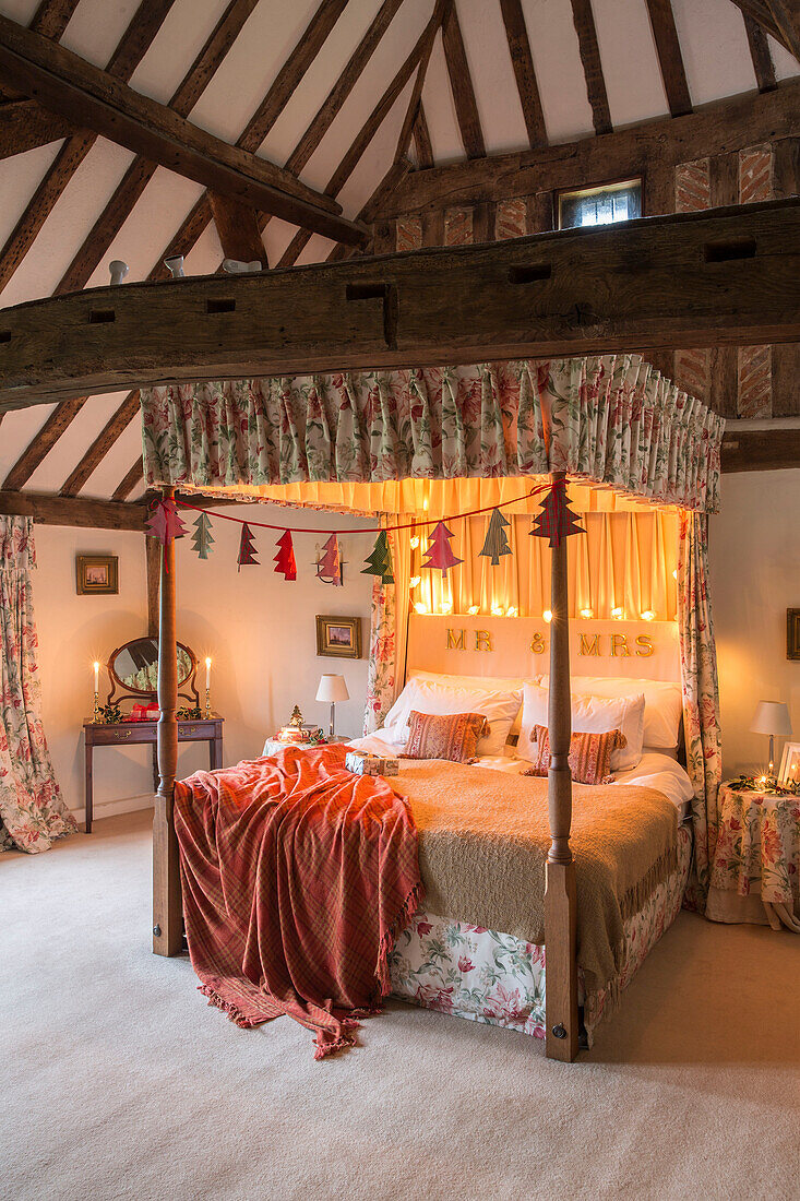 Beleuchtete Lichter auf einem Himmelbett mit abgestimmten Stoffen in einem Bauernhaus in Hampshire, England, UK