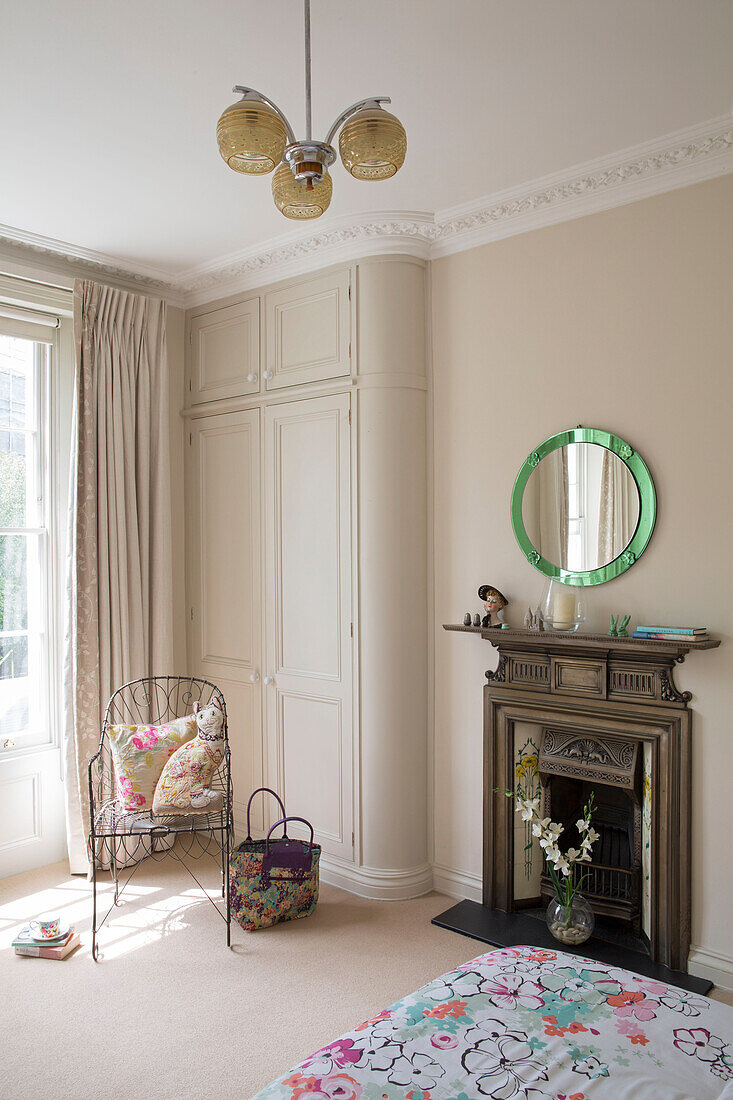 Metal chair at fireside in London townhouse bedroom UK