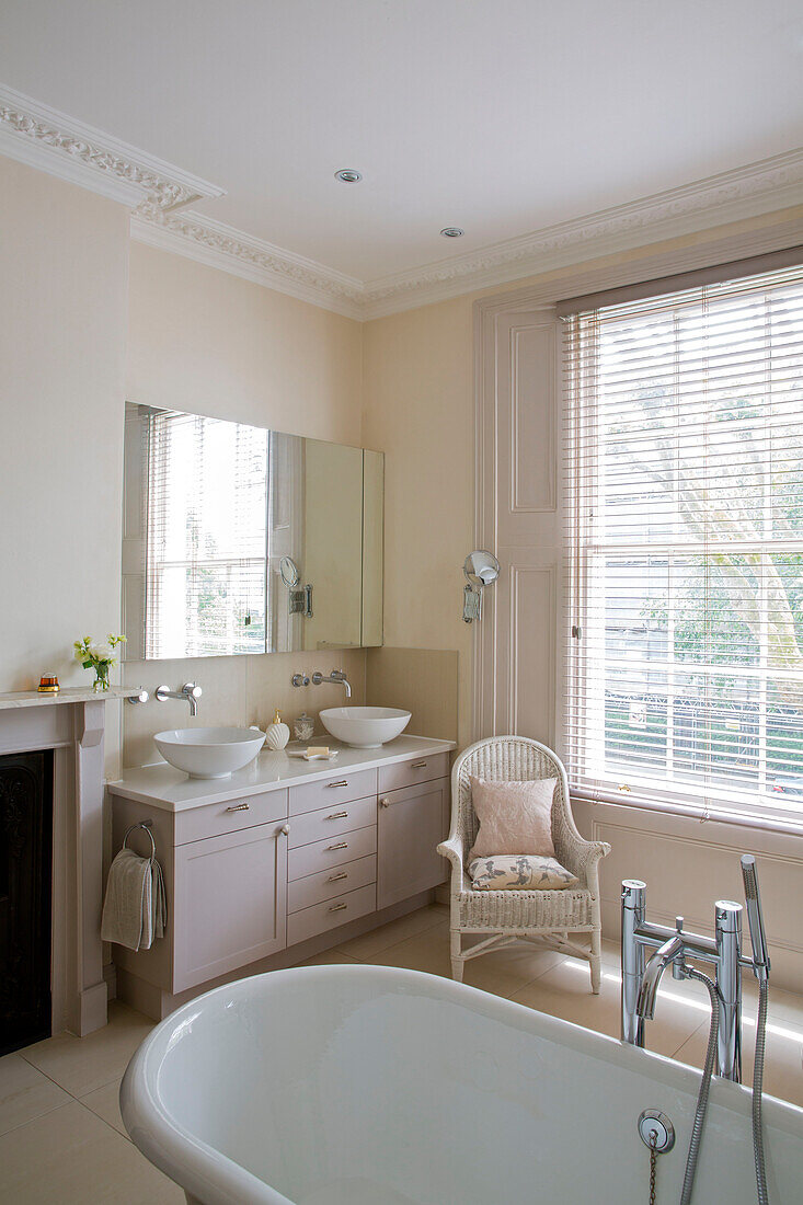 Double basins and wicker chair with freestanding bath in London townhouse UK