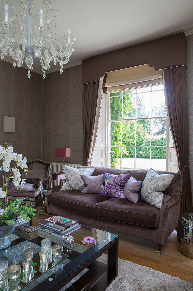 Cushions on brown sofa with glass topped coffee table in detached Sussex country house UK