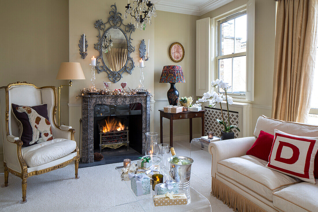 Gilt armchair and lamps at fireside with decorative mirror in London townhouse UK