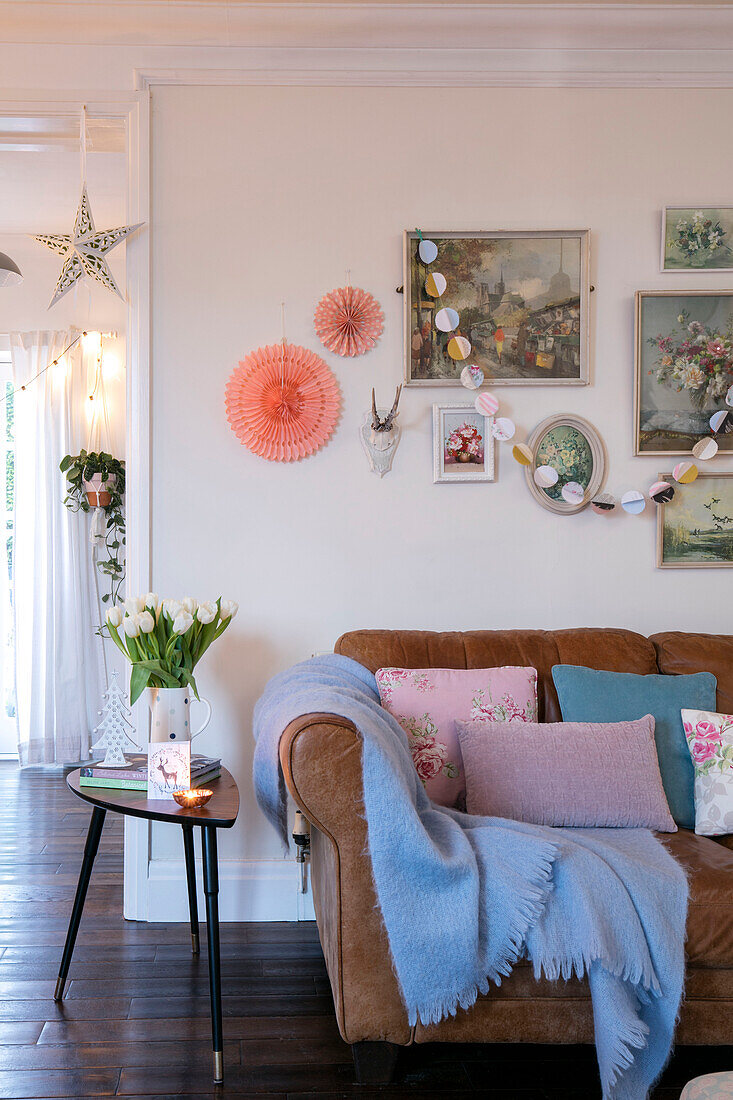 Weihnachtsschmuck und Tulpen mit blauer Decke auf dem Sofa in einem viktorianischen Cottage aus dem 19