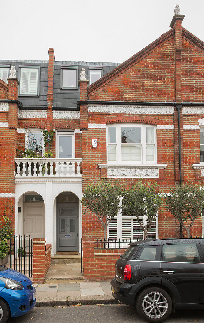 Cars parked outside brick London townhouse UK