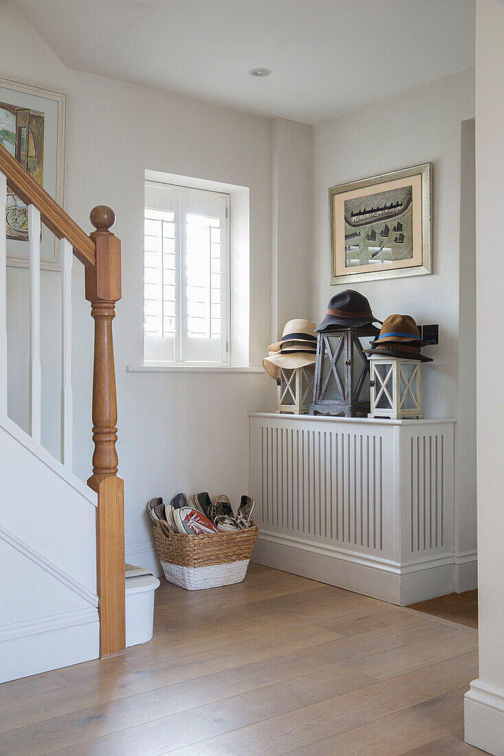 Sonnenhüte und Laternen mit Schuhen in einem Korb im Flur eines Hauses in West Sussex