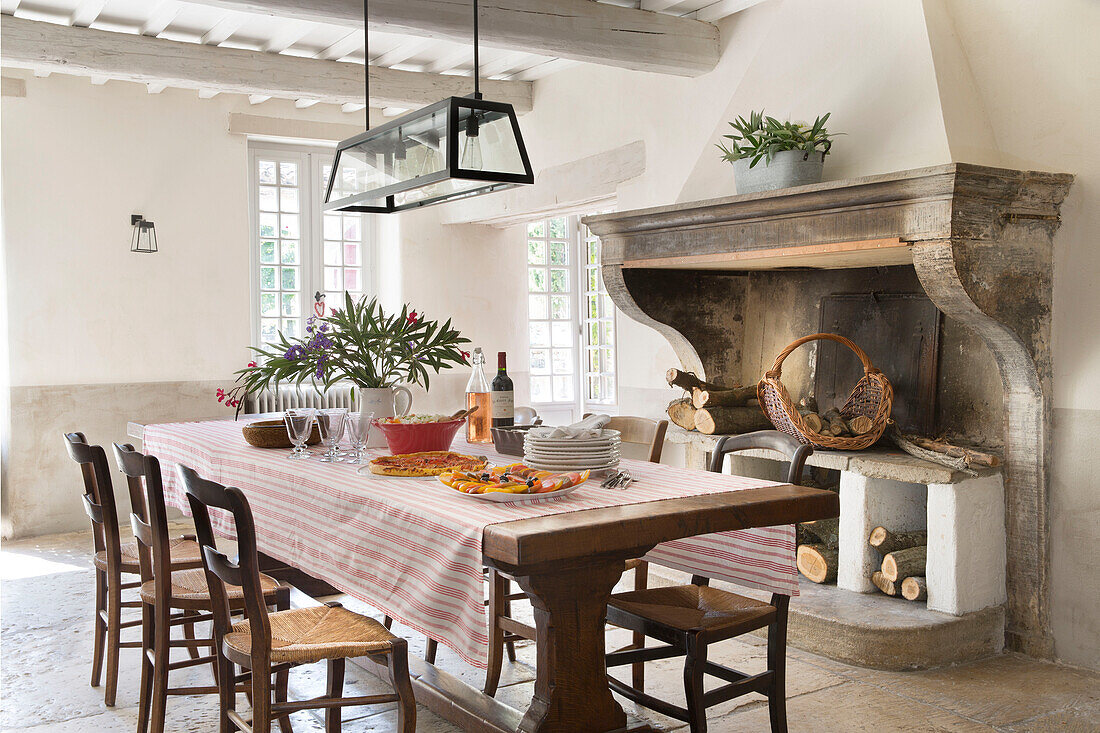 Moderner Glaslampenschirm über dem Esstisch mit originalem Kamin in einem provenzalischen Bauernhaus aus dem 19