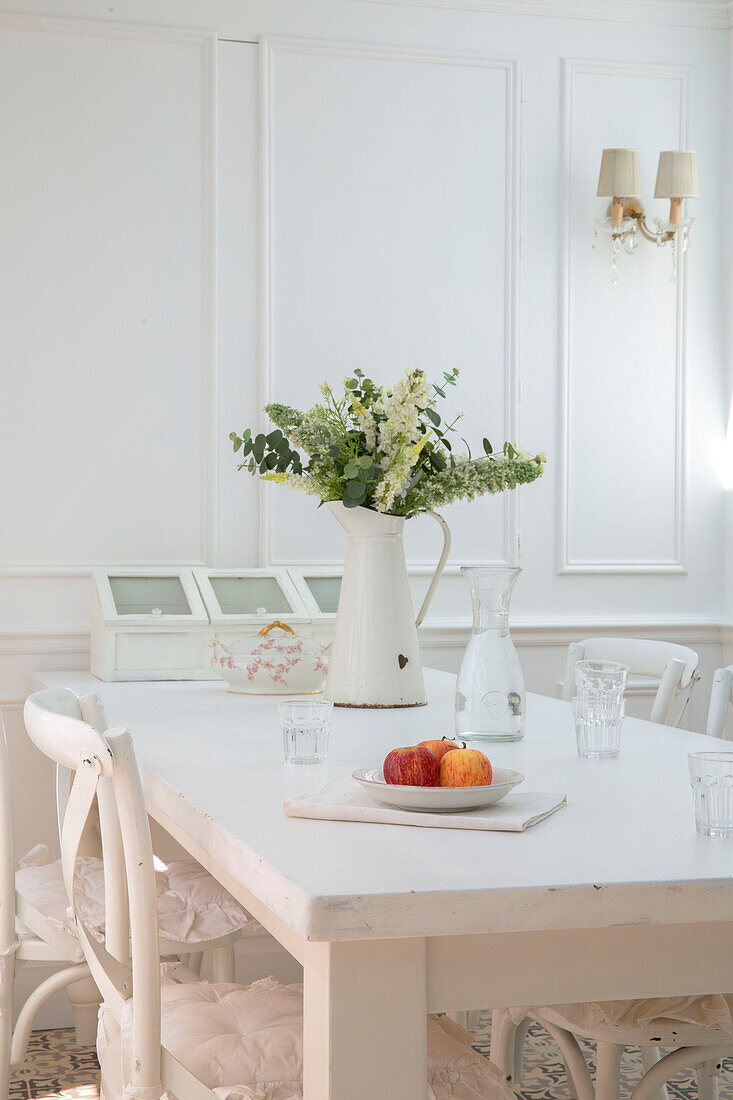 Schnittblumen und Äpfel auf weißem Esstisch mit Stühlen in einem edwardianischen Haus in Surrey, Großbritannien