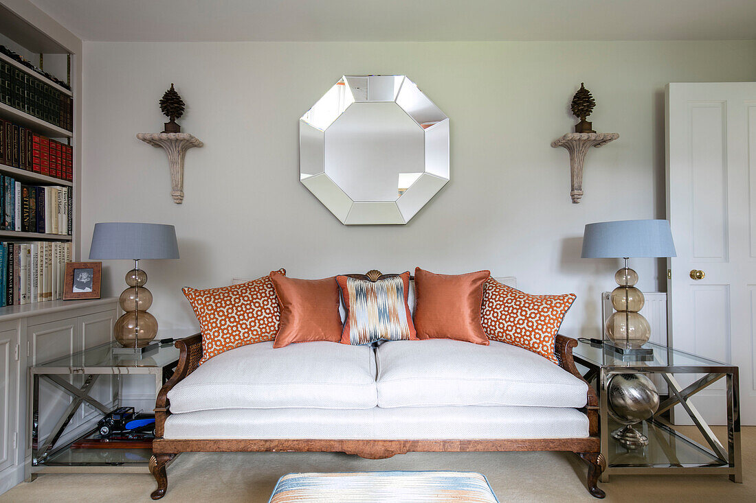 Hexagonal mirror above vintage daybed with matching lamps on tables in Wiltshire home England UK