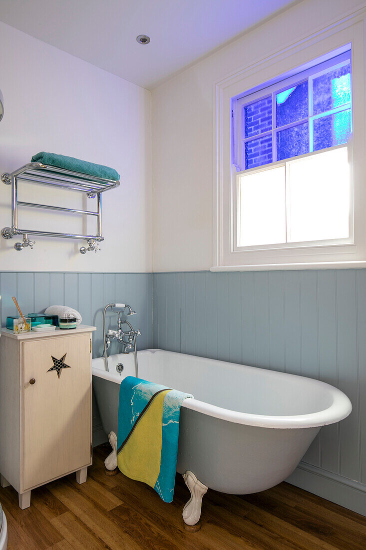 Freestanding bath below window with light blue tongue and groove panelling in terraced Sevenoaks home Kent UK