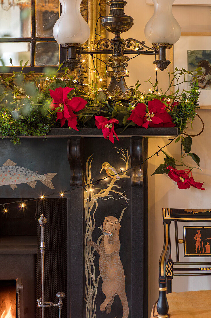 Poinsettia and lanterns on black stone fireplace in hallway of Georgian home Hertfordshire England UK