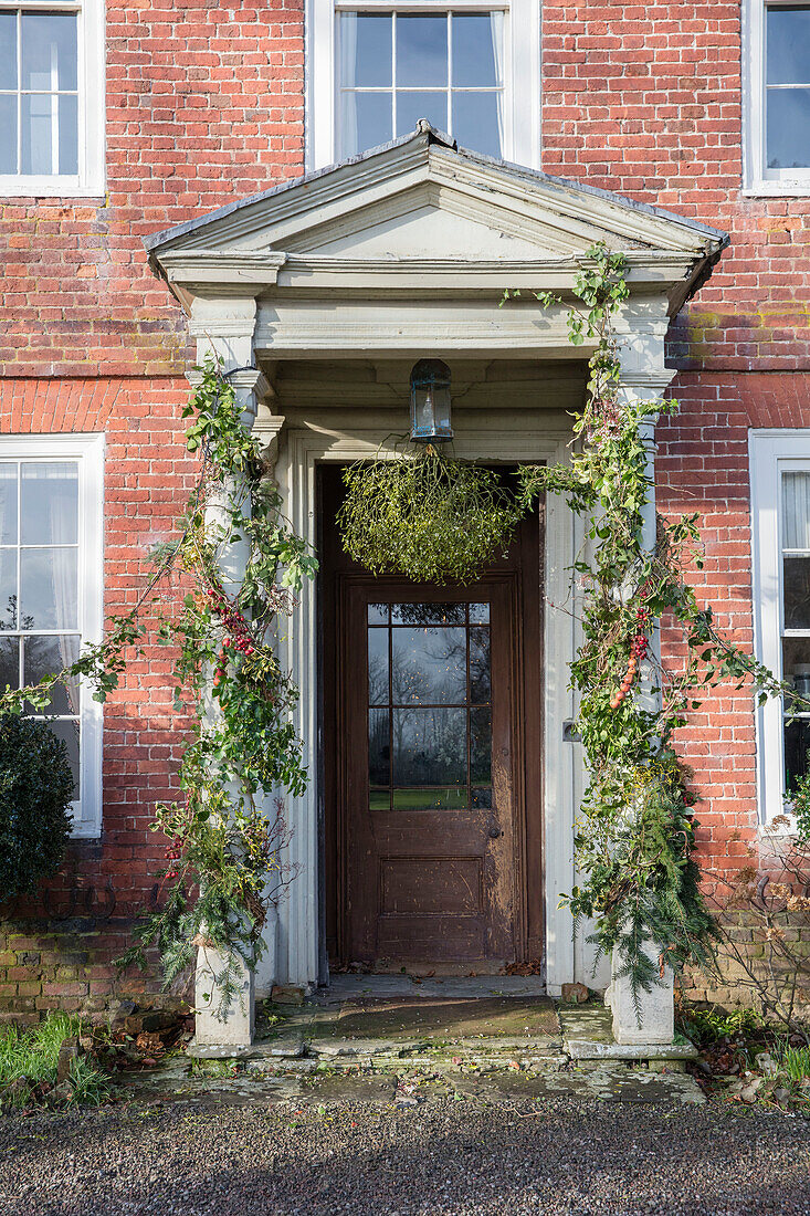 Mistletoe and Christmas garlands on stone porch of Georgian house Hertfordshire England UK