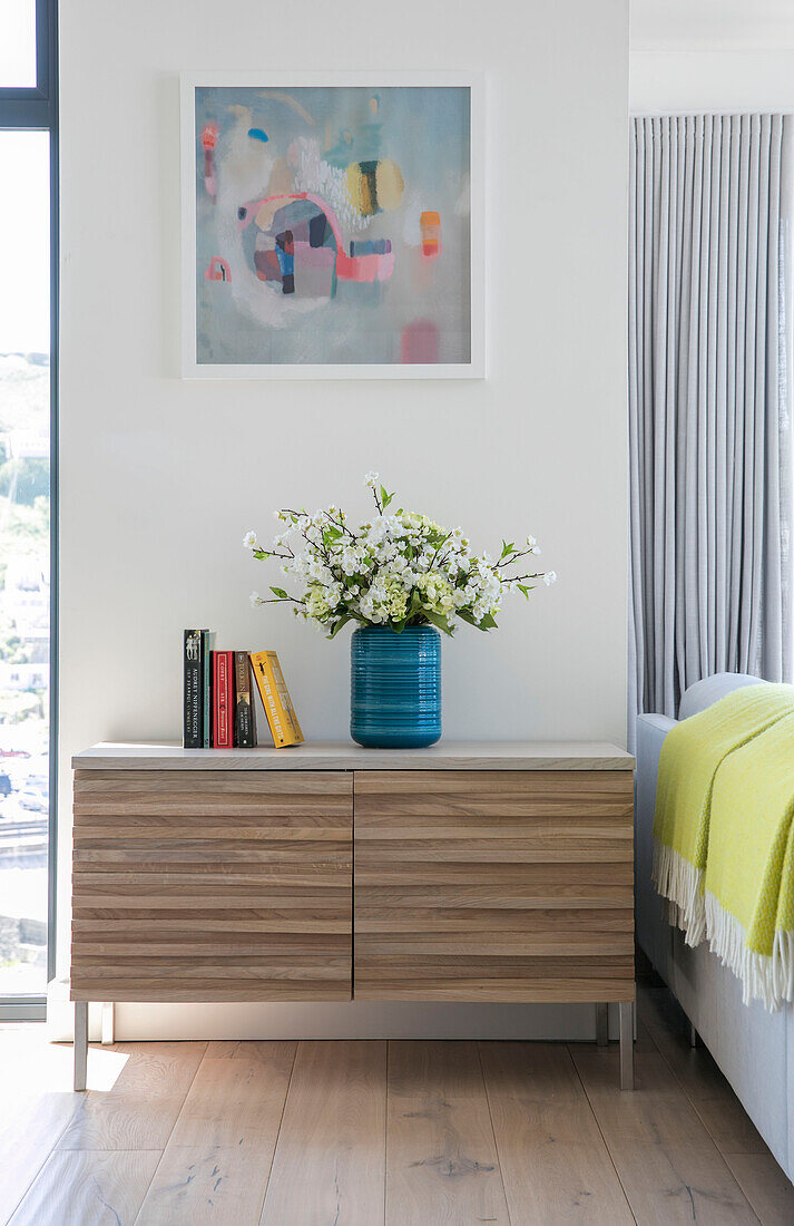 Cut flowers on wooden sideboard with artwork in newbuild Cornwall UK