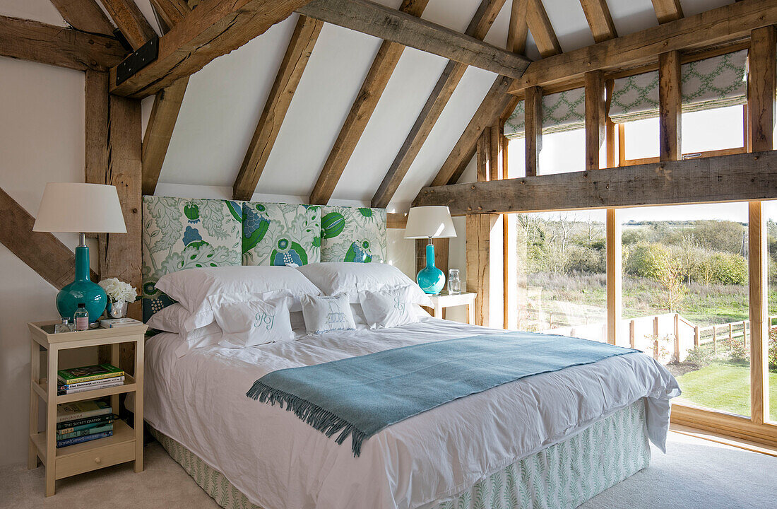 Turquoise lamps with blue blanket on double bed in Hampshire barn conversion UK