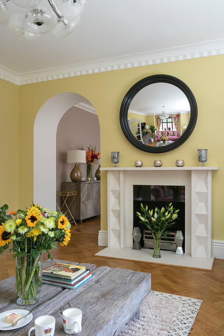 Convex mirror with cut flowers in modernised 1900s Arts and Crafts style London home UK