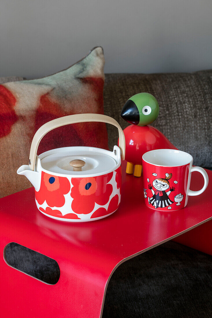 Teacup and toy with cup on bright red breakfast tray in North London home UK