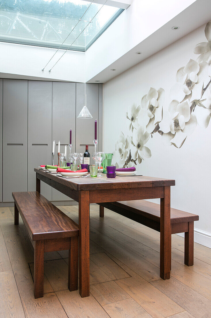 Large floral wall deco with wooden table and benches below skylight in North London renovation UK