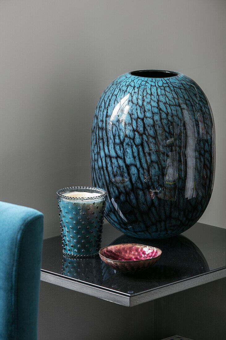 Ceramic teal vase and candle holder on side table in London home UK