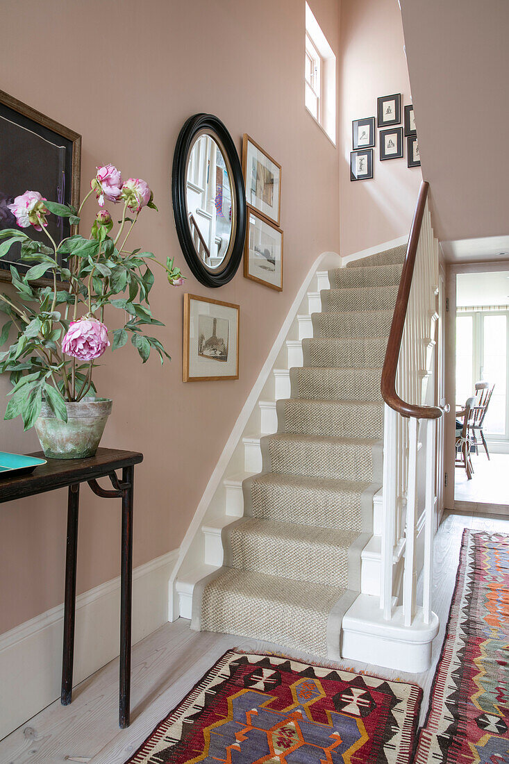 Peony on console in hallway with circular mirror over stairs London home UK