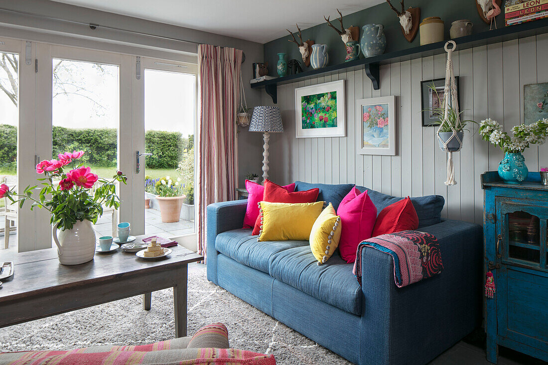 Graues Sofa mit hellen Kissen und Couchtisch vor Terrassentüren in einem Haus in Hampshire England UK