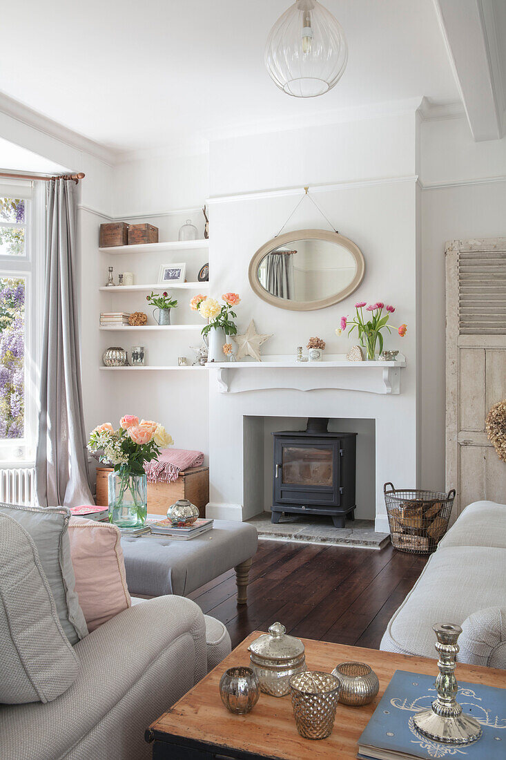 Silverware on side table with mirror above fireplace in pastel grey living room of Grade II listed country house Hertfordshire UK