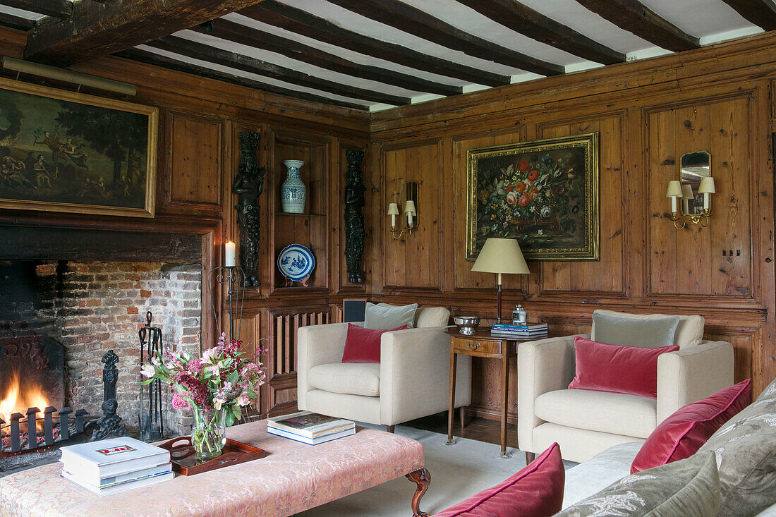 Cream armchairs with pink velvet cushions in wood panelled Kent farmhouse UK