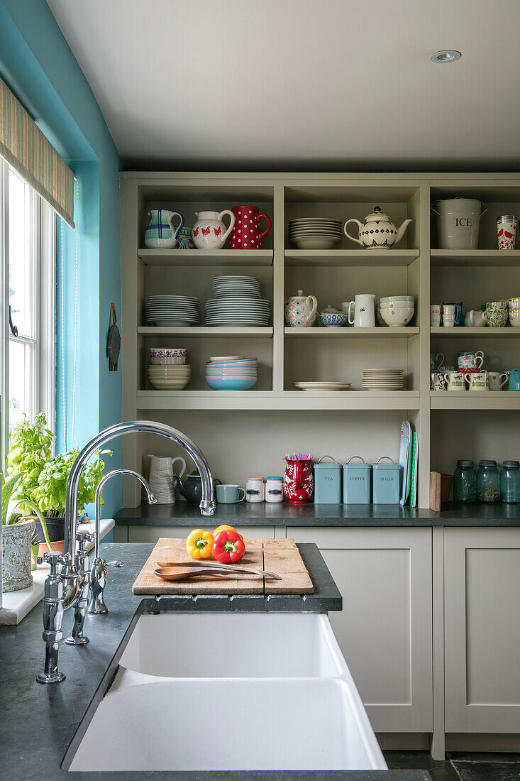 Double sink at kitchen window with open shelving in Hampshire home England UK