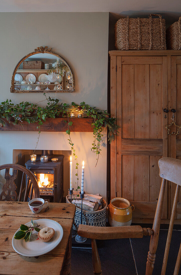 Wooden furniture with mirror and garland above lite fire in Georgian Hampshire cottage dining room UK