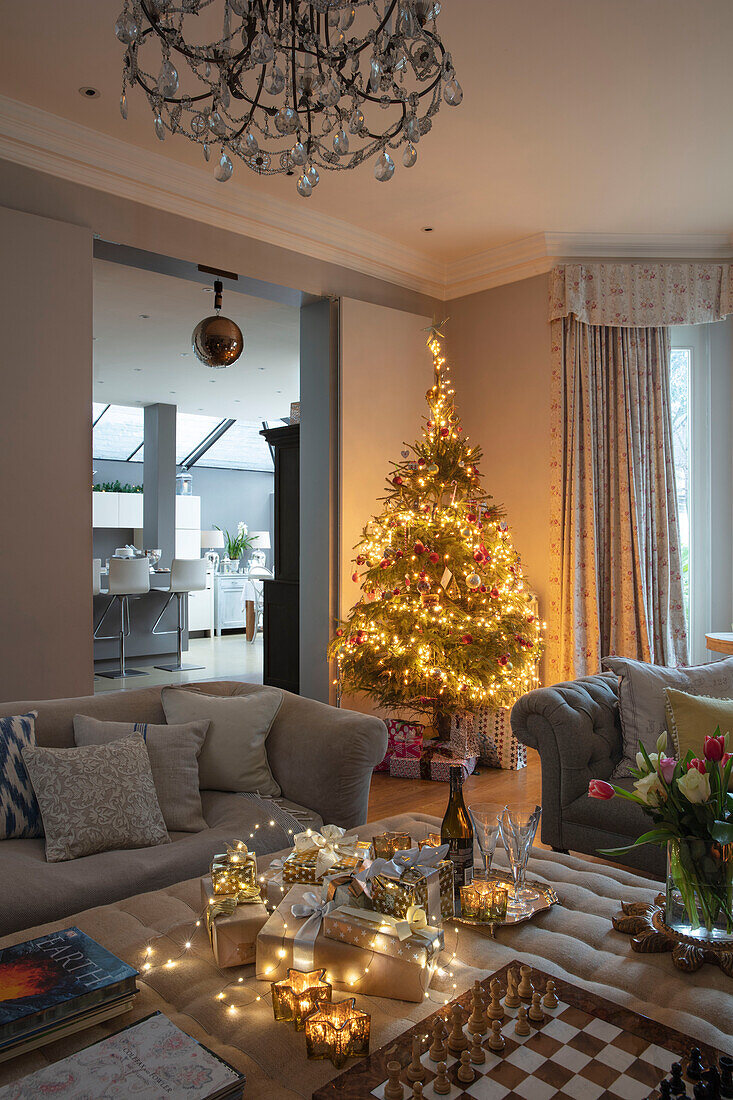 Beleuchteter Weihnachtsbaum und Geschenke mit Blick auf die Küche in einem Haus in London UK